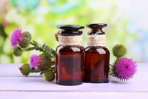 Medizinflaschen mit Distelblumen auf Naturhintergrund — Stockfoto