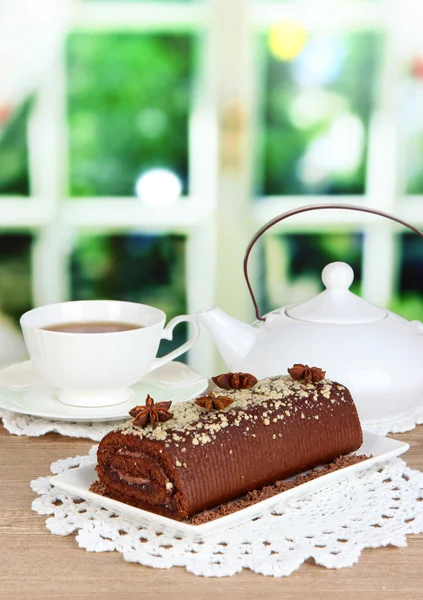 Rollo dulce con taza de té en la mesa en la habitación — Foto de Stock