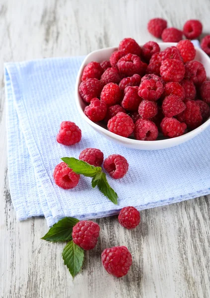 Reife süße Himbeeren in Schale auf Holzgrund — Stockfoto