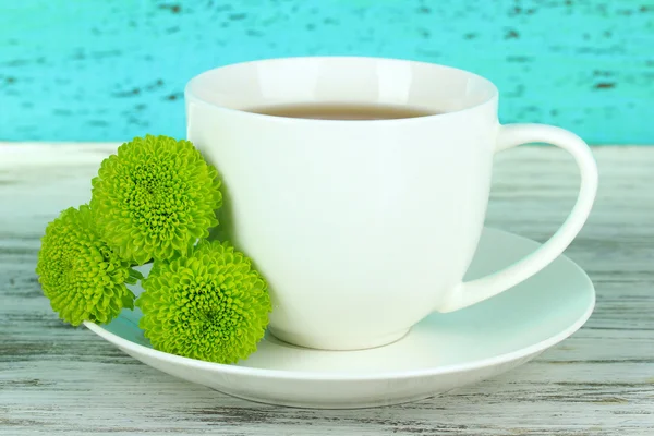 Beautiful green chrysanthemum with cup of tea on table on blue background — Stock Photo, Image