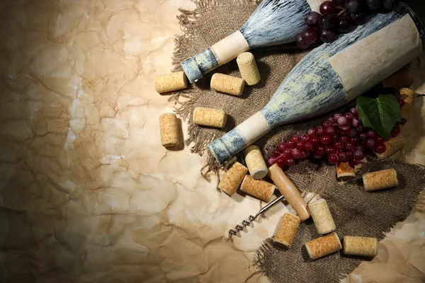 Garrafas velhas de vinho, uvas e rolhas no fundo de papel velho — Fotografia de Stock