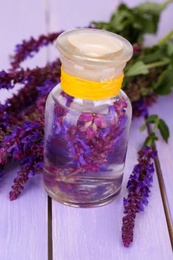 Ada çayı çiçekler mor ahşap zemin ile ilaç şişesi