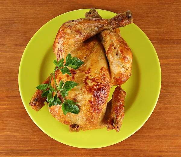 Roasted whole chicken on a green plate on wooden background — Stock Photo, Image