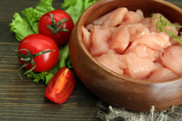 Raw chicken meat in bowl, on wooden background — Stock Photo, Image