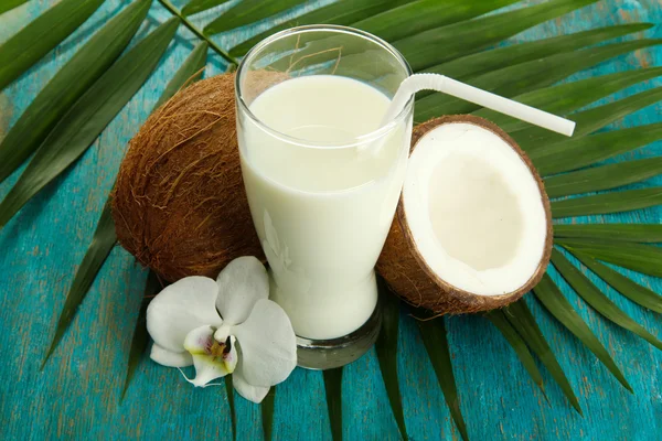 Cocos con vaso de leche, sobre fondo azul de madera — Foto de Stock