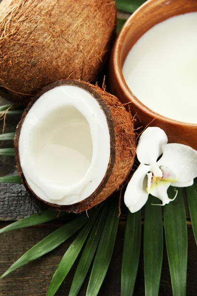 Noix de coco avec feuilles et fleurs, sur fond bois gris — Photo