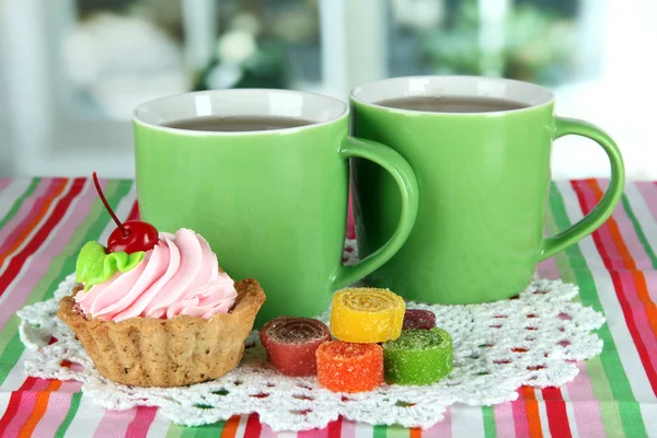 Cups of tea with cake and candy on table in room — Stock Photo, Image