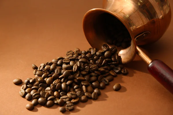 Panela de café com grãos de café no fundo marrom — Fotografia de Stock