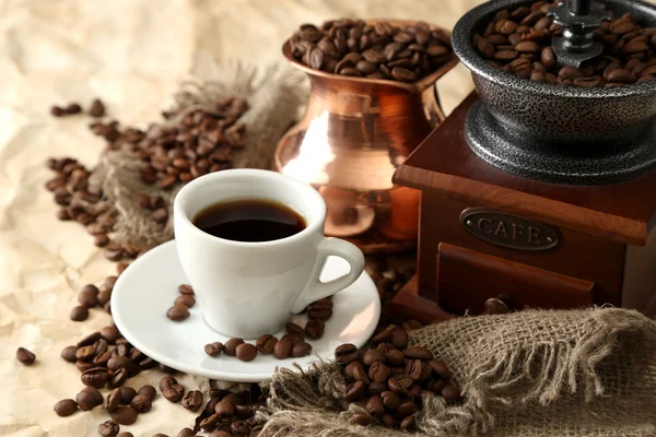 Cup of coffee, pot and grinder on beige background — Stock Photo, Image