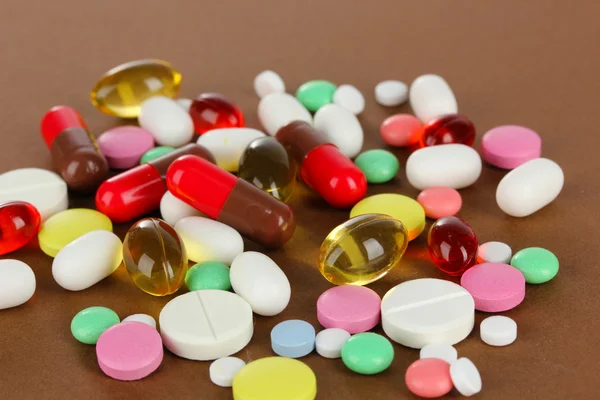 Assortiment van pillen, tabletten en capsules op bruine achtergrond — Stockfoto