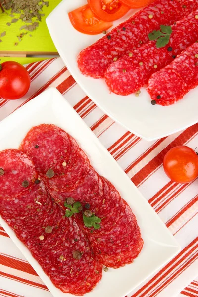 Leckere Salami auf Tellern auf Holztisch in Großaufnahme — Stockfoto