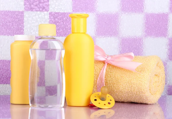 Baby cosmetics and towel in bathroom on violet tile wall background — Stock Photo, Image