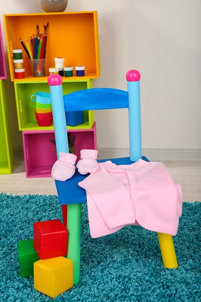 Cadeira pequena e colorida com roupas de bebê — Fotografia de Stock