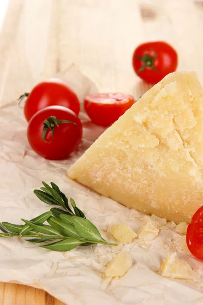 Pedazo de queso parmesano sobre papel sobre mesa de madera primer plano — Foto de Stock