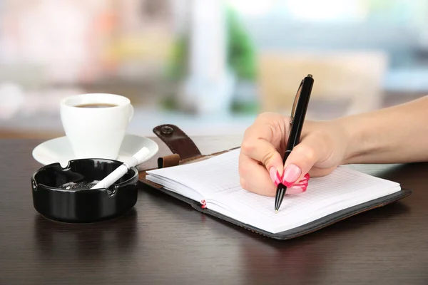 Hand signing in notebook, on bright background — Stock Photo, Image