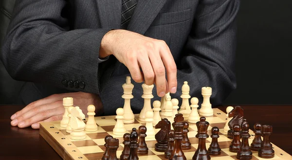 黒の背景にチェスをしている若いビジネスマン — ストック写真