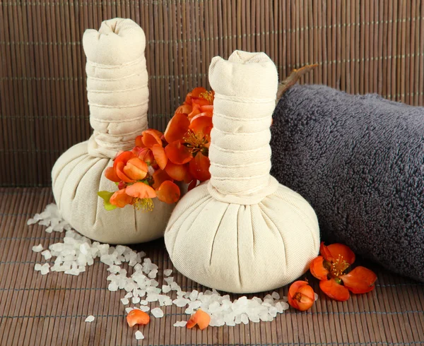 Herbal compress balls for spa treatment and towel on bamboo background