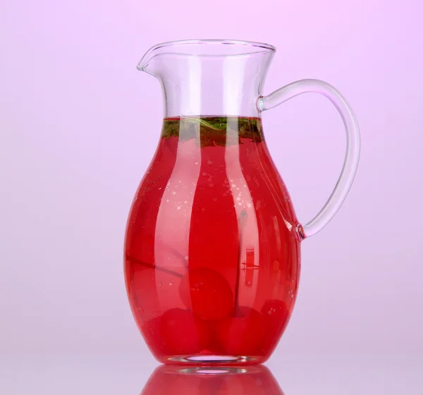 Cherry drink in pitcher on purple backgroun — Stock Photo, Image