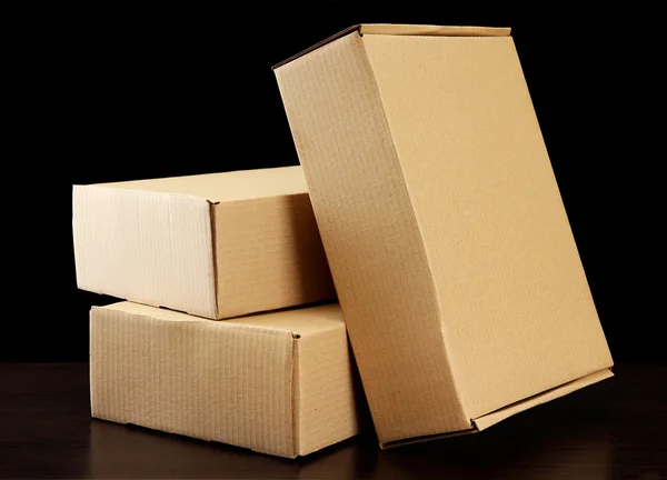 Parcels boxes on wooden table, on black background — Stock Photo, Image