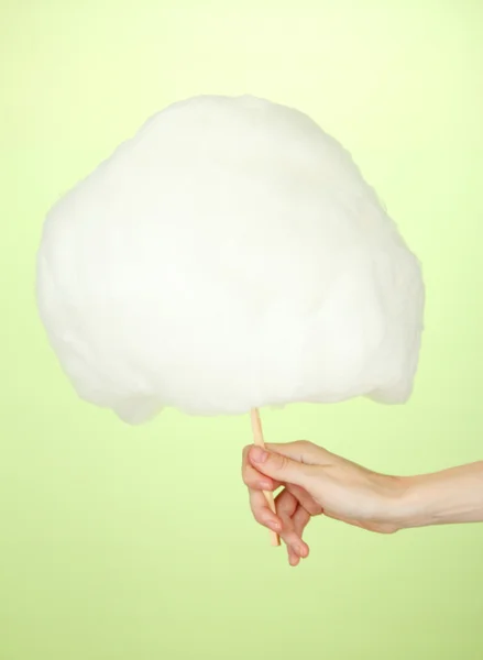 Hand holding stick with cotton candy, on color background — Stock Photo, Image