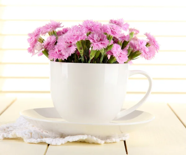 Many small pink cloves in cup on wooden background — Stock Photo, Image