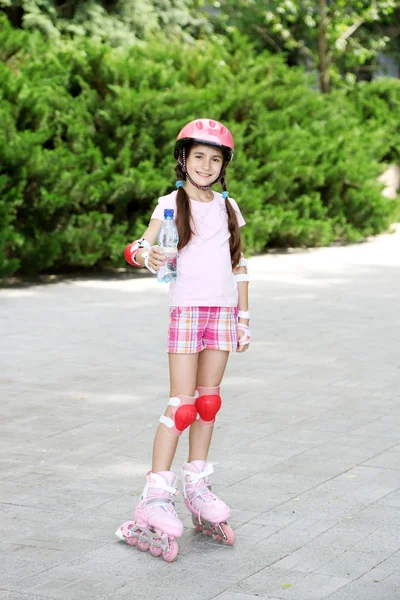 Little girl in roller skates drinking water at park — Stock Photo, Image