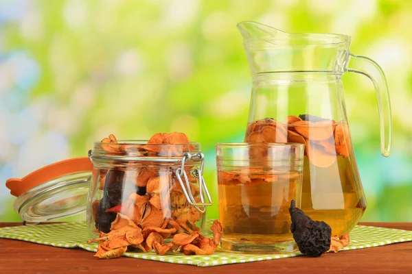 Assorted dried fruits in bank and compote of dried fruits on wooden table on natural background — Stock Photo, Image