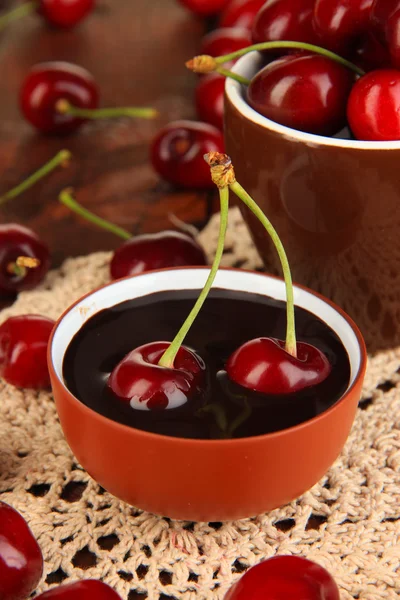 Olgun kırmızı kiraz meyveleri ahşap masa yakın çekim Kupası ve çikolata sosu — Stok fotoğraf