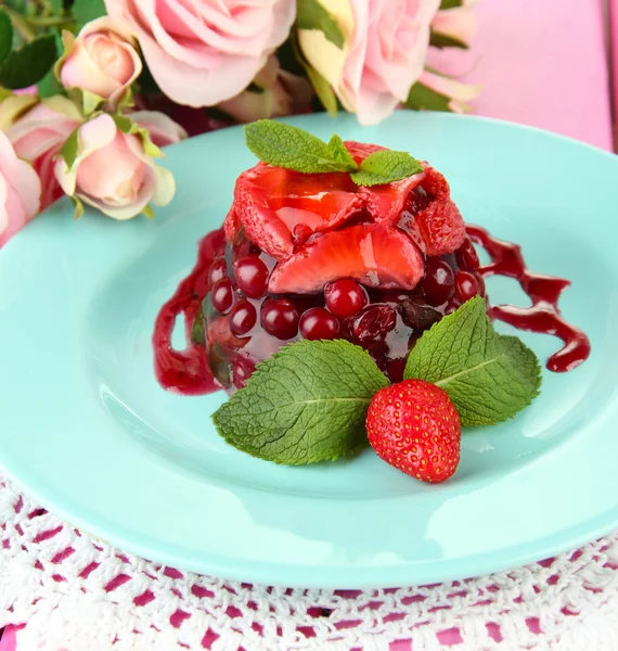 Sobremesa de geleia saborosa com bagas frescas, em fundo de rosas rosa — Fotografia de Stock