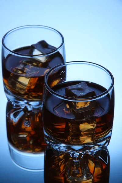 Copas de brandy con hielo sobre fondo azul —  Fotos de Stock