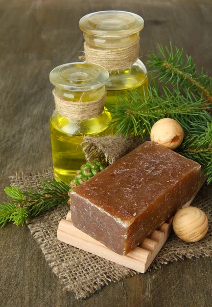 Sapone fatto dalla mano e bottiglie di olio di abete su sfondo di legno — Foto Stock