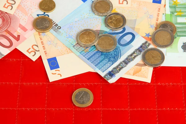 Euro banknotes and euro cents on red background — Stock Photo, Image