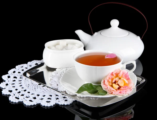 Kettle and cup of tea from tea rose on metallic tray on napkin black background — Stock Photo, Image