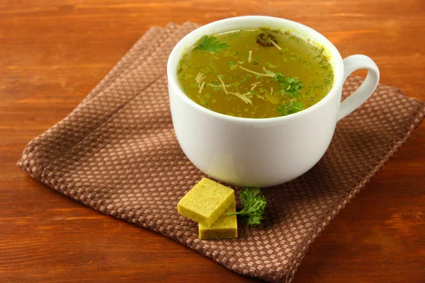 Xícara de sopa com cubos de caldo em fundo de madeira — Fotografia de Stock