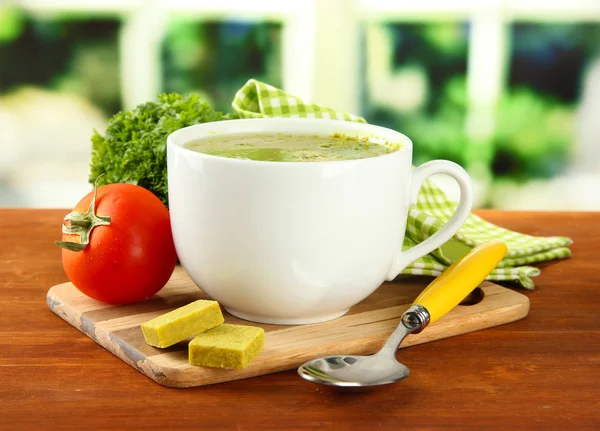 Copa de sopa con cubos de caldo sobre mesa de madera — Foto de Stock