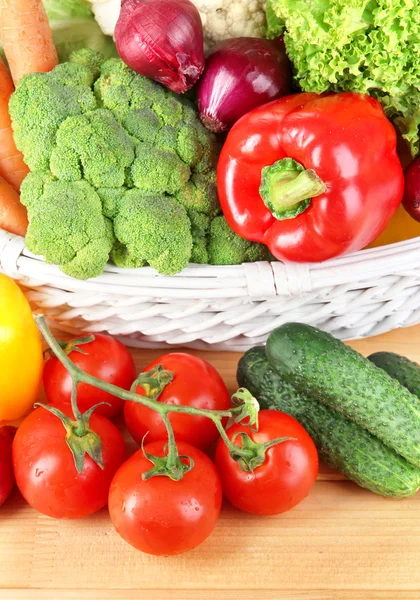 Fresh vegetables in white wicker basket on wooden background — Stock Photo, Image