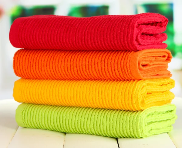 Kolorowe ręczniki na drewnianym stole na tle okna — Zdjęcie stockowe
