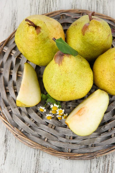 Birnen auf geflochtenem Tablett auf Holztisch — Stockfoto