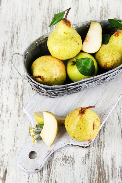 Pears in basket on board on wooden table — Stock Photo, Image