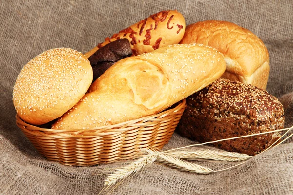 Pečený chleba v proutěném koši na pytlovina pozadí — Stock fotografie
