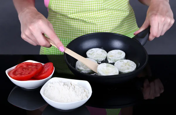 Manos cocinando calabacines en sartén sobre fondo gris — Foto de Stock