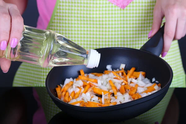Manos cocinando cebolla frita con zanahoria en sartén sobre fondo gris —  Fotos de Stock