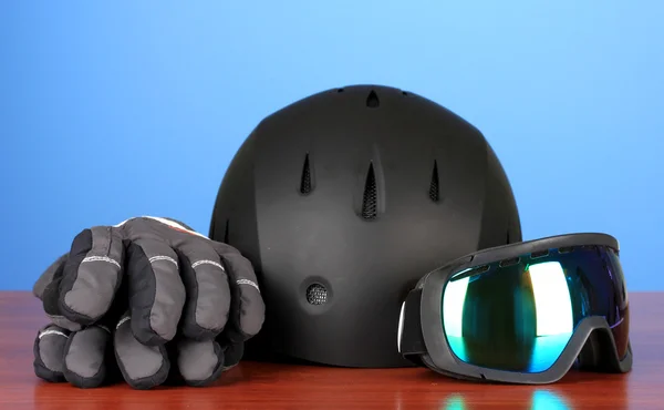 Zimní sportovní brýle, helmu a rukavice, na modrém pozadí — Stock fotografie