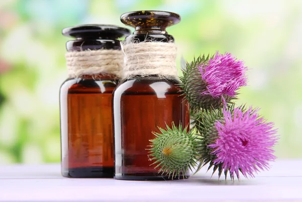 Medizinflaschen mit Distelblumen auf Naturhintergrund — Stockfoto