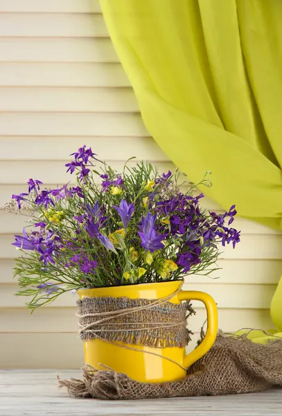 Mooi boeket van wilde bloemen in cup op houten tafel — Stockfoto