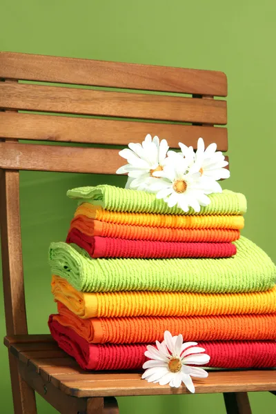 Toallas y flores en silla de madera sobre fondo verde — Foto de Stock