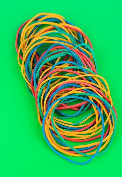 Colorful rubber bands on green background — Stock Photo, Image