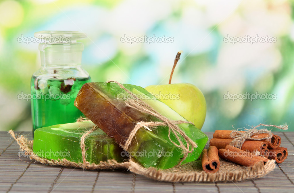 Hand made soap and ingredients for soap making on bamboo mat, on green background