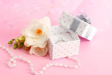 Alyans ve çiçek pembe bir arka plan üzerinde güzel kutusu