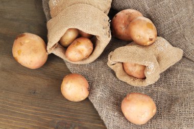ahşap masa üstünde çul üzerine çuval patates
